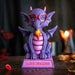 Figurine of a dragon sitting on a pink base that says "I LOVE DRAGONS!" The dragon is purple and pink with red heart glasses and a little burst of fire.