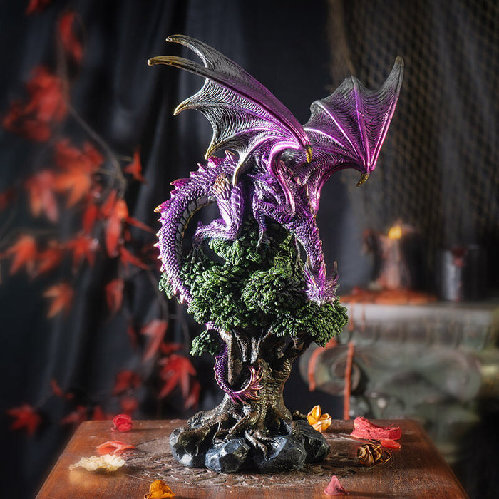 Figurine of a metallic purple dragon perched on a green tree