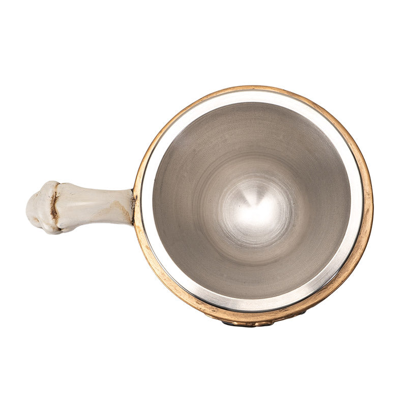 Teacup with stainless steel insert. Skeleton couple embraces against a black background with gold accents and red roses. Faux-bone handle.