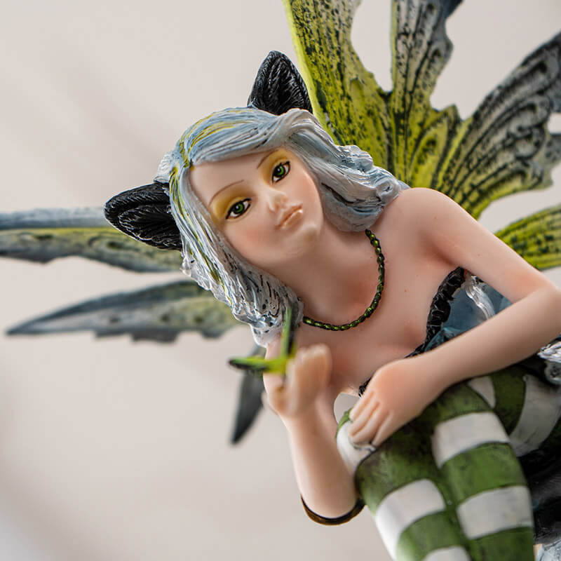Figurine of fairy with green wings and striped stockings, and black cat ears. Holding a butterfly with a black winged fairy cat next to her