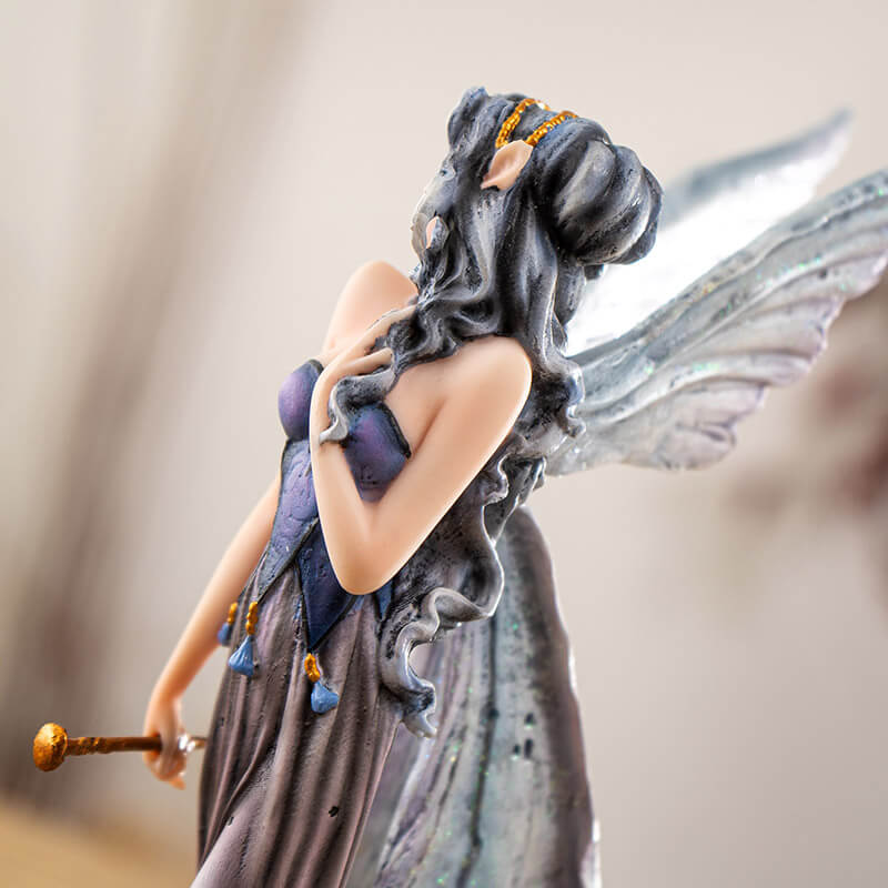 Figurine of fairy with gray wings and hair and purple dress walking with two tan wolves. Fae carries a gold wand.
