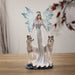 Fairy queen in a white dress with pale hair and blue wings. She stands with two white wolves, a hand on each of their heads. Small size
