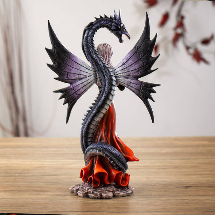 Figurine of fairy in black and red holding a rose, with a black snake dragon wrapped around her protectively. Back view