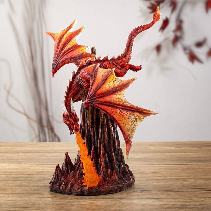 Figurine of a red dragon flying over rocks, breathing a column of orange fire