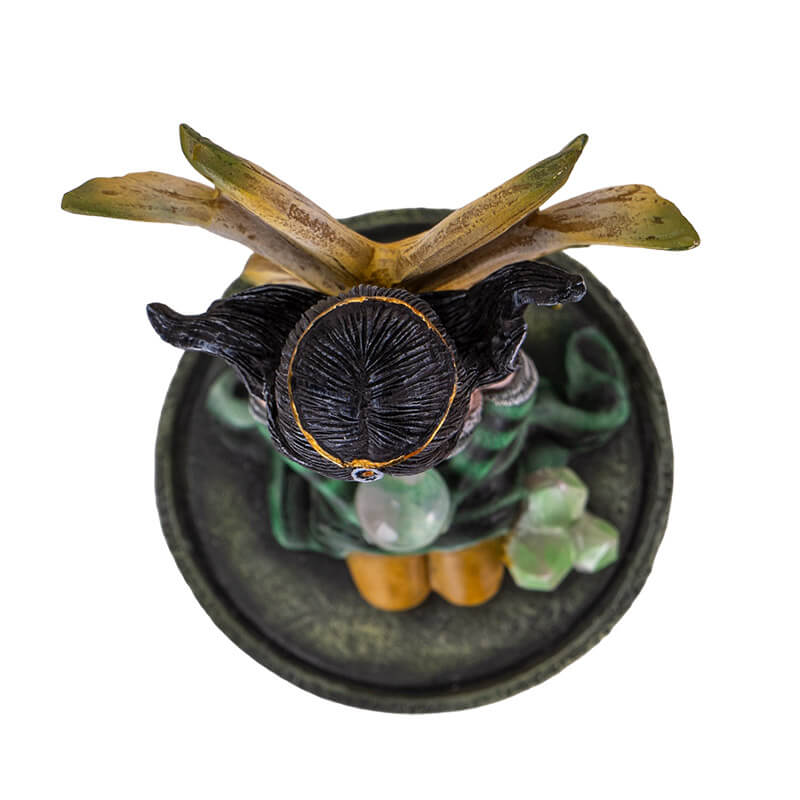 Figurine of kneeling fairy in green, black and yellow with black hair holding a crystal ball on her lap, with crystals next to her