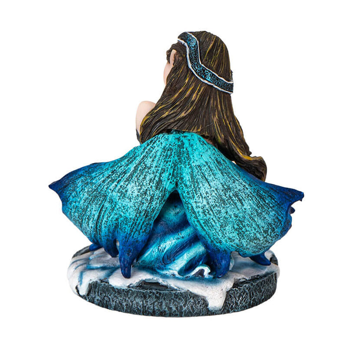Figurine of brunette fairy in blue dress sitting in snow by a crystal cluster, holding crystal ball