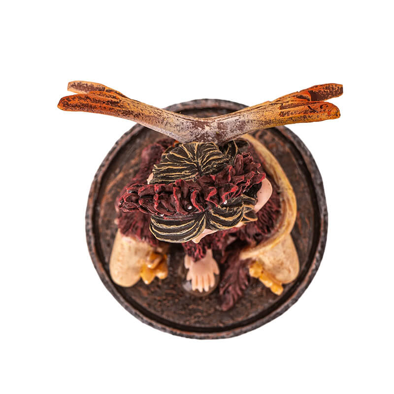 Figurine of fairy in red and orange with lion mane and tail, sitting with gem clusters in yellow and crystal ball. Top down view