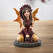 Figurine of fairy in red and orange with lion mane and tail, sitting with gem clusters in yellow and crystal ball