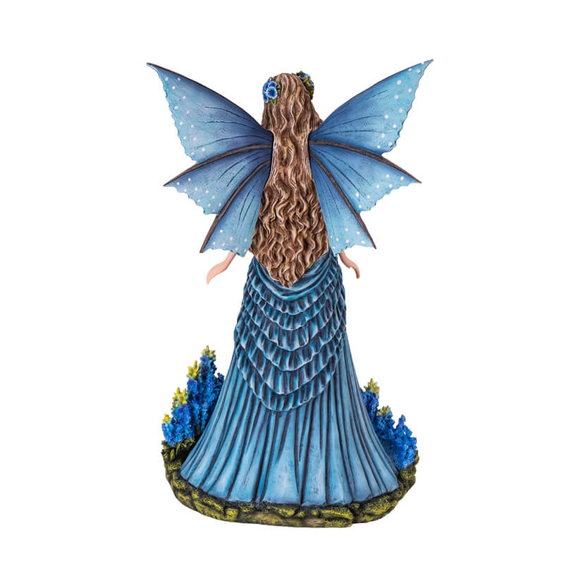 Figurine of a fairy in a blue dress with detailed blue wings and long hair, standing with bright indigo flowers.