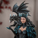 Figurine of a woman in black and blue dress with glitter and flowing cape, and a black and blue dragon on her shoulder.