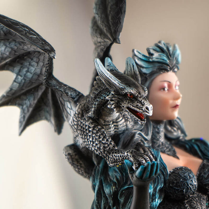 Figurine of a woman in black and blue dress with glitter and flowing cape, and a black and blue dragon on her shoulder.