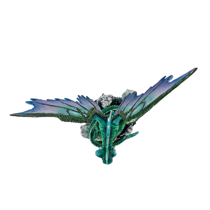 Figurine of green water dragon with emerald and blue wings rising from dark, foamy waves. Top down view