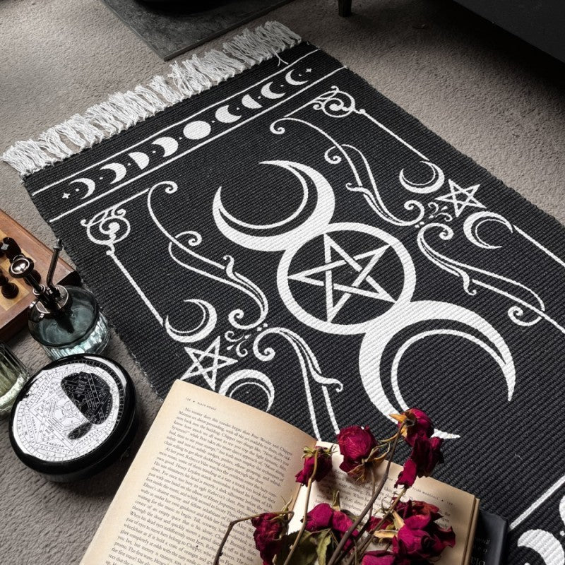 Black and white floor rug with triple moon and stars design, shown with books and such