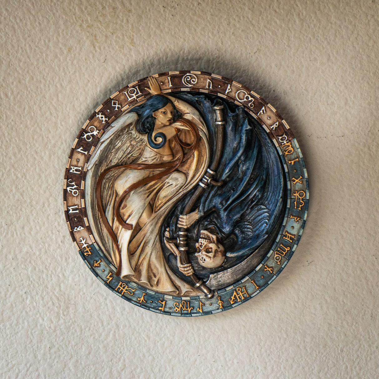 Wall plaque, angel on one side, ivory with blue hair and grim reaper with ivory skull on the other side, runes around the circular edges