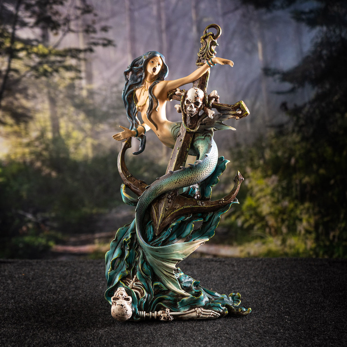 Figurine of a mermaid wrapped around an anchor with a skeleton and seaweed