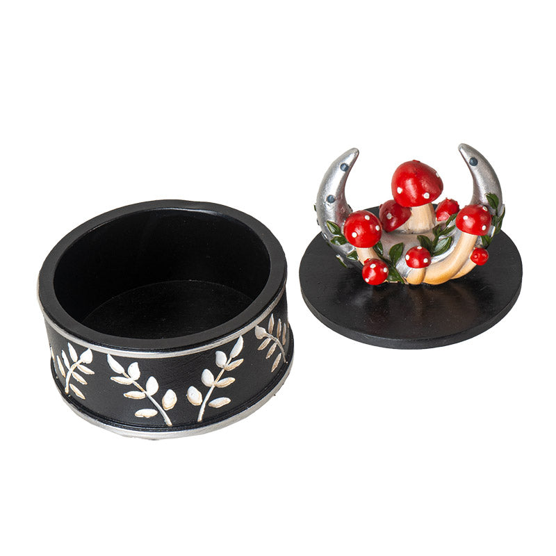 Trinket box with silver moon and red and white mushrooms on the lid, sprigs of leaves around outside of bottom of vessel in white on black. Shown open