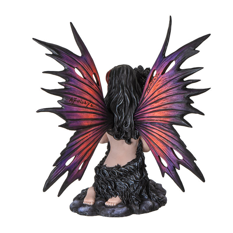 Figurine of fairy with red and purple wings kneeling on stone, black wolf face with fur wrapping around the tattooed pixie, shown from the back