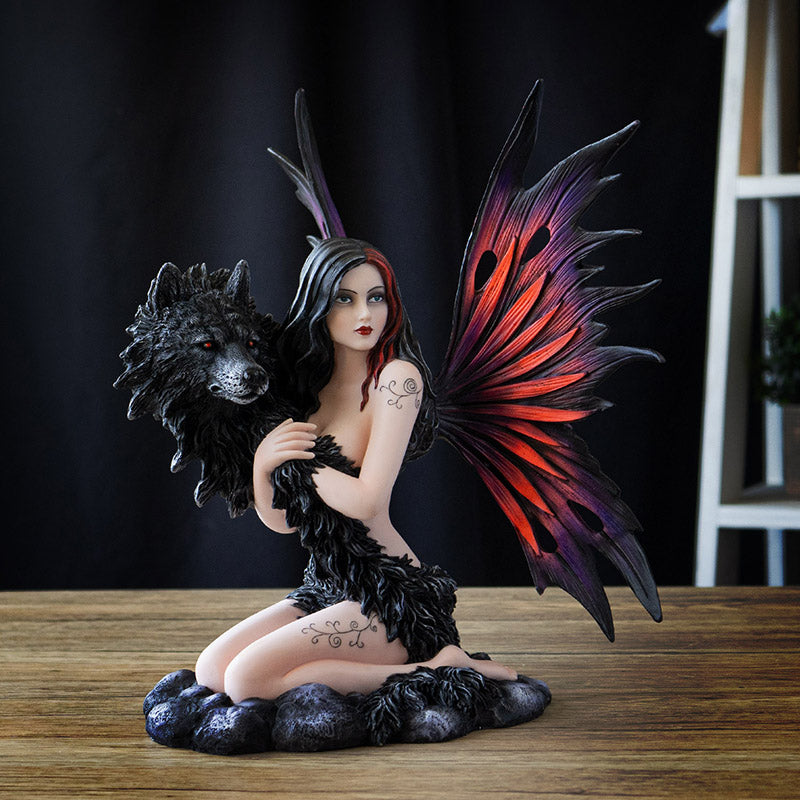 Figurine of fairy with red and purple wings kneeling on stone, black wolf face with fur wrapping around the tattooed pixie