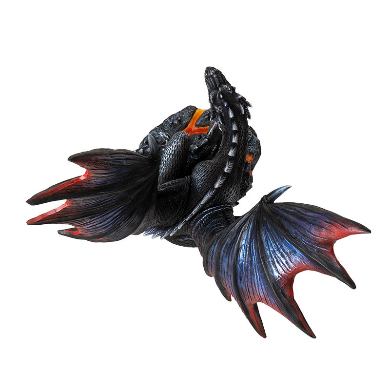 Figurine of a black dragon with blue, red, orange accents, perched snarling on a rocks with lava. Shown top-down