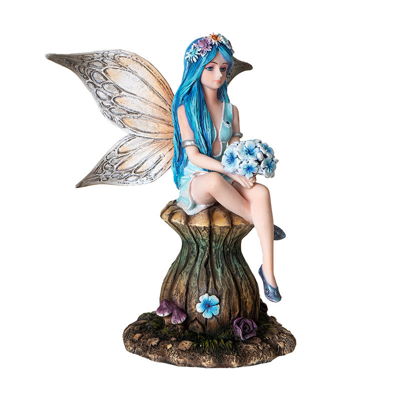 Figurine of fairy with blue hair and tan wings holding blue flower bouquet, sitting on mushroom