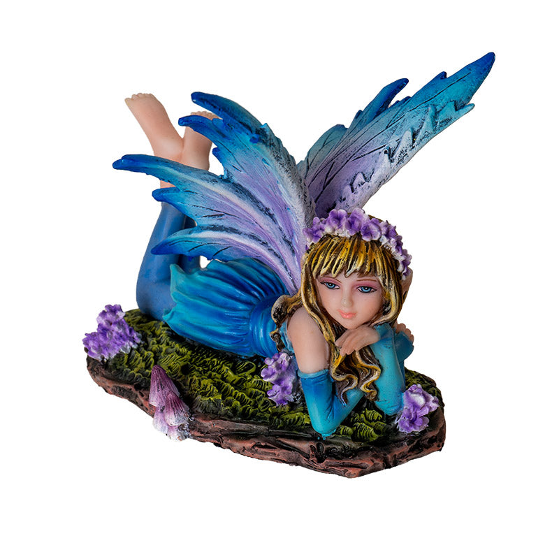 Fairy figurine - pixie laying down, wearing blue dress with leggings and feet kicked up behind her. Blue wings, purple flower and mushroom accents
