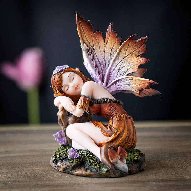 Fairy figurine, brown-orange dress, hair, wings, sleeping on a stump