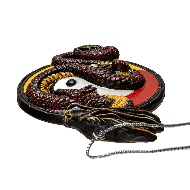 Ornament of red-brown Asian dragon with yellow belly curled around white and black yin yang circle on a red and yellow background, shown top down