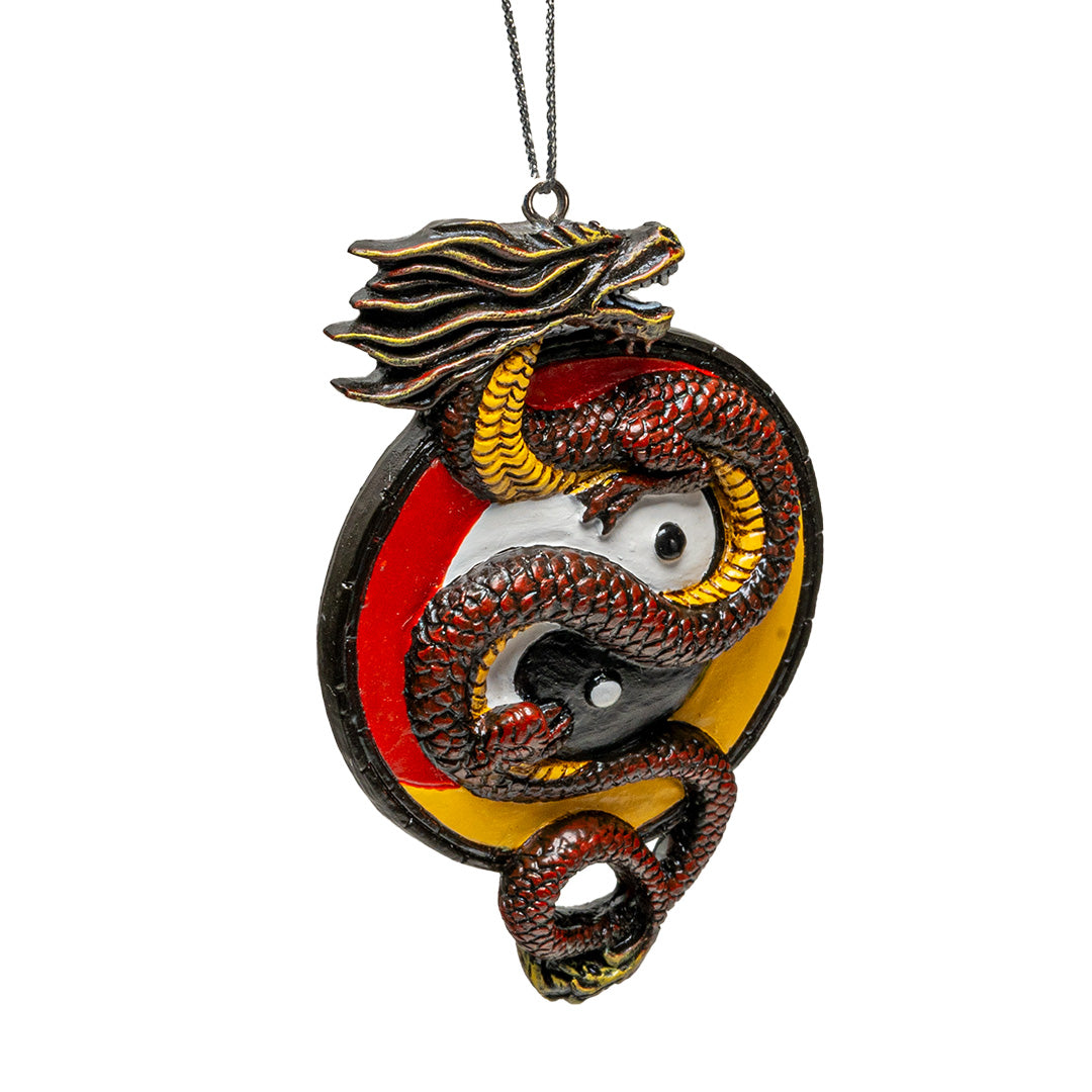 Ornament of red-brown Asian dragon with yellow belly curled around white and black yin yang circle on a red and yellow background