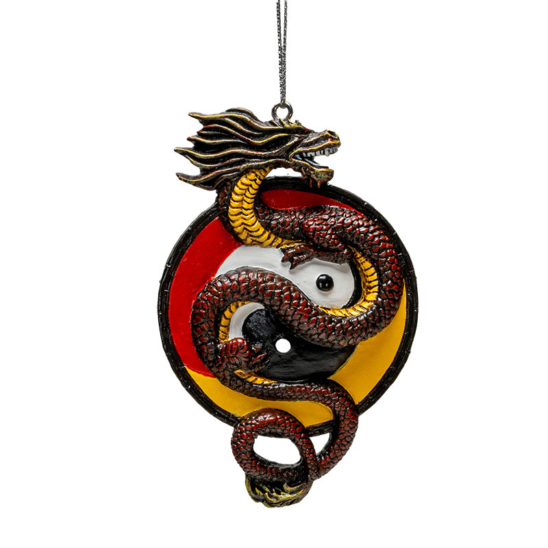 Ornament of red-brown Asian dragon with yellow belly curled around white and black yin yang circle on a red and yellow background