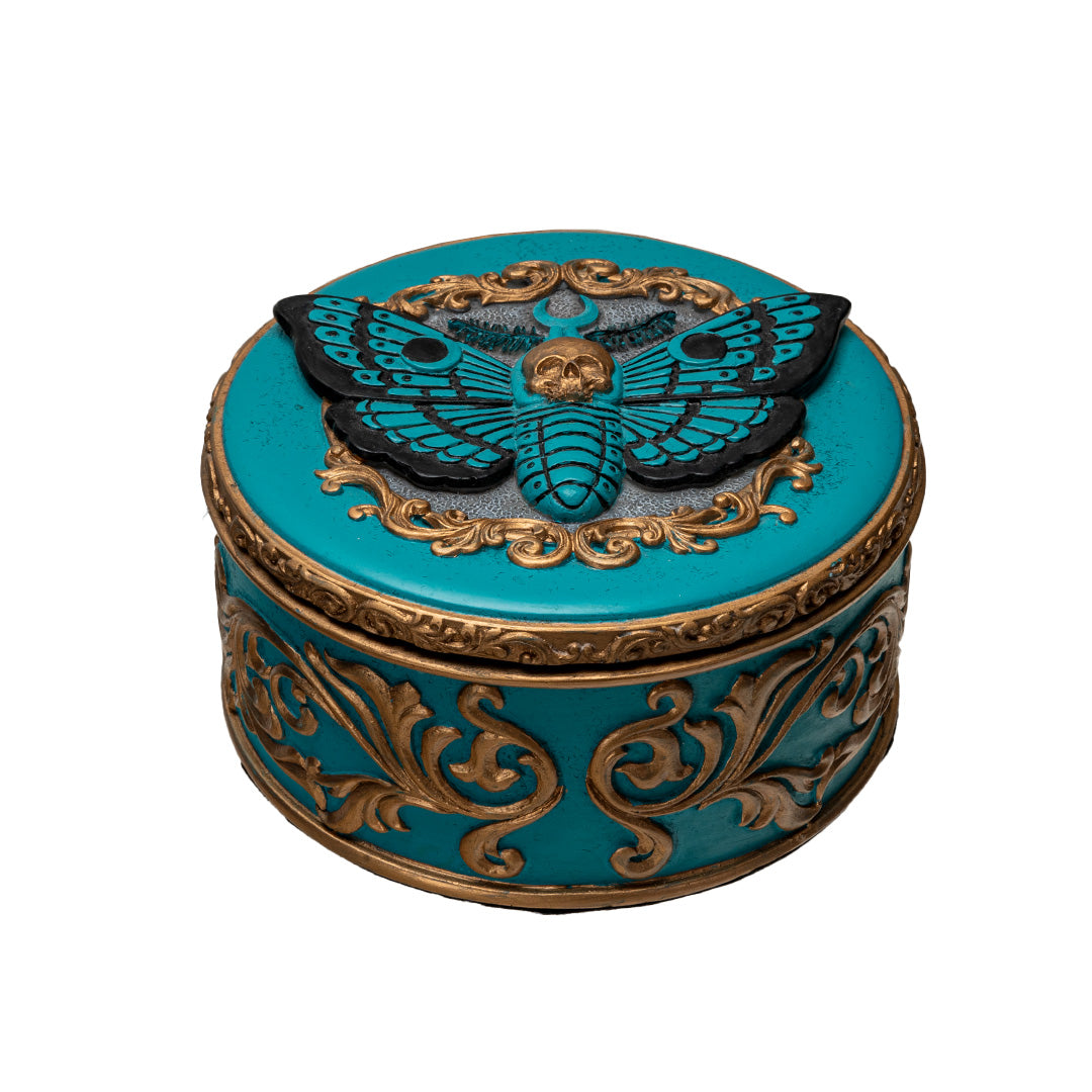 Round trinket box with blue base and moth design, gold accents, skull and swirls