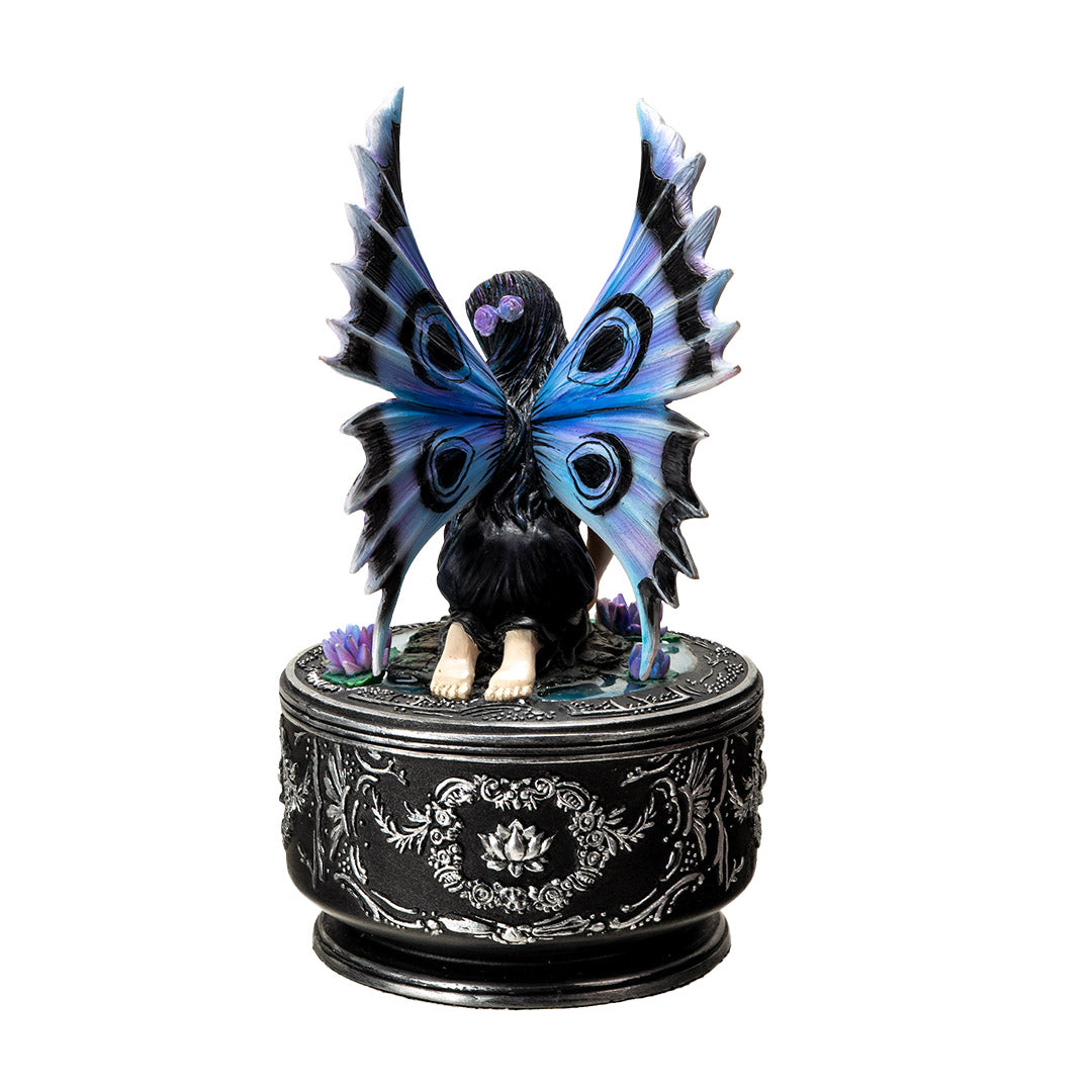 Trinket box with black base and silver designs. On the lid is a fairy in black dress with purple and blue wings accented in black, sitting amidst water lilies. Shown from the back
