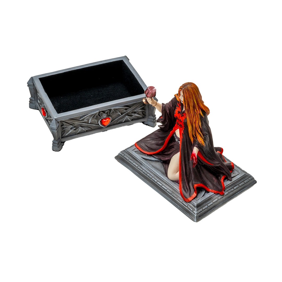 Trinket box, faux stone gray coffin with bat motif and red heart jewel. On lid is a vampire lady with 1 bloody hand and other holding a goblet, crimson and black skirt and top, auburn hair, fangs. Shown with lid off