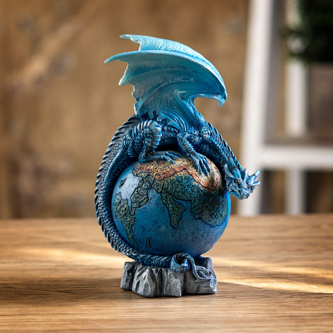 Dragon figurine, perched on planet earth. Blue dragon with tail curled around the globe