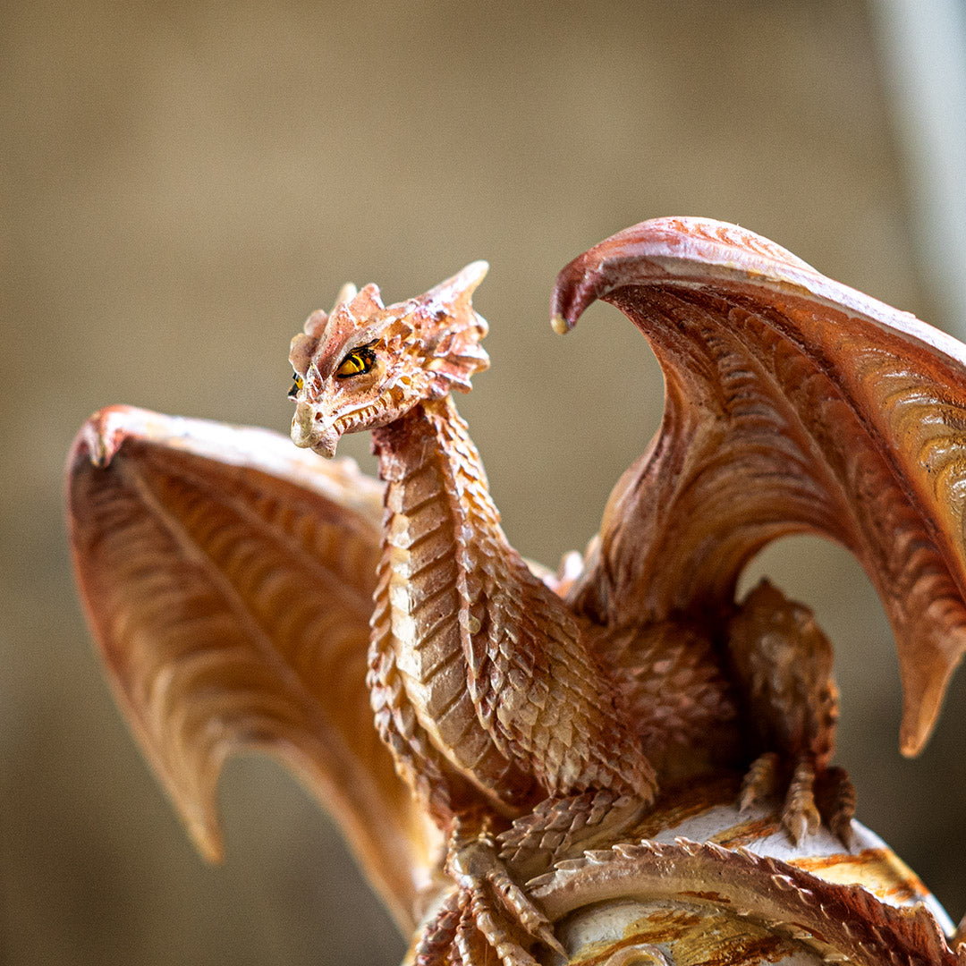 Closeup of tan dragon with detailed scales, yellow-orange eyes, wings out to either side