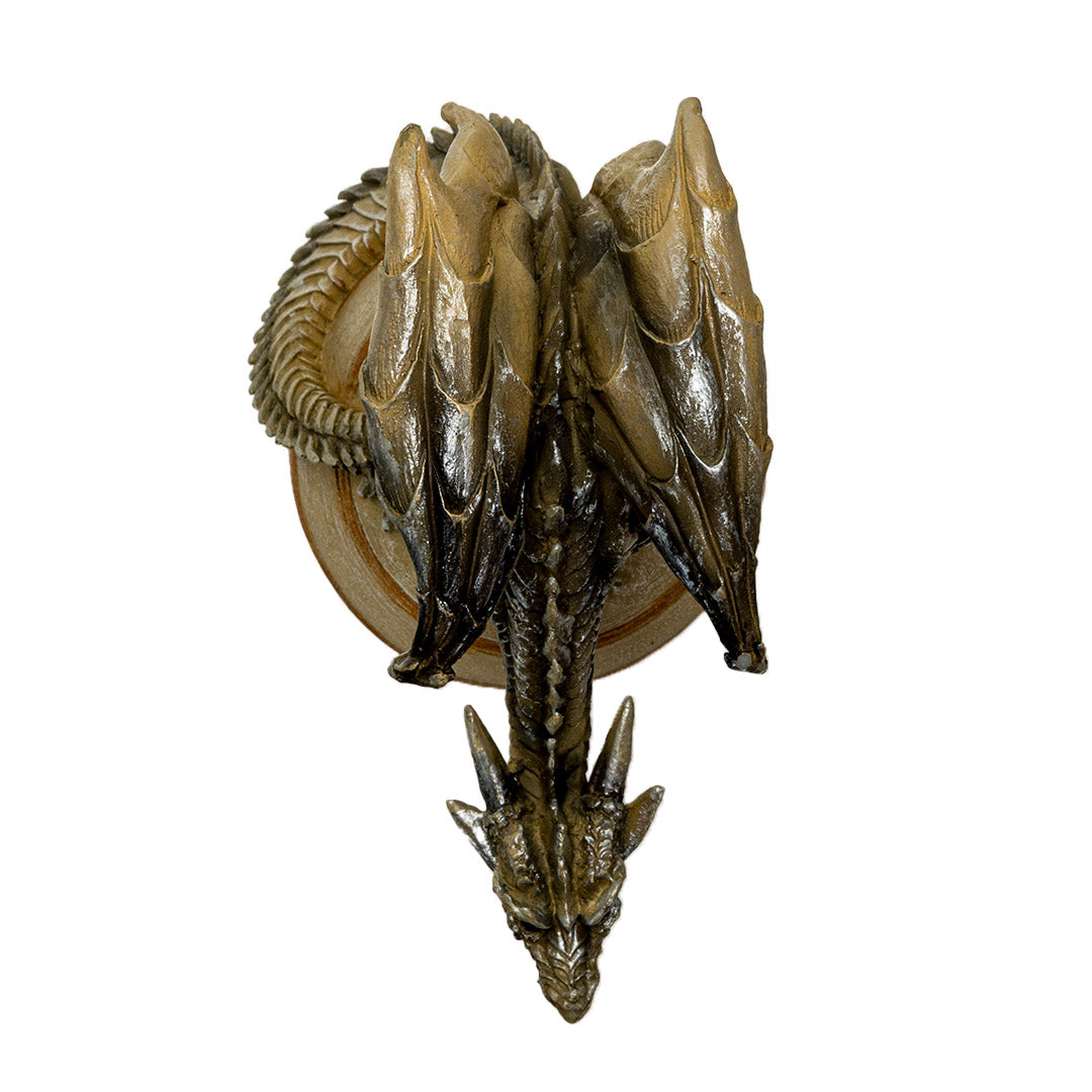 Figurine of a brown dragon perched upon the tan planet Saturn on a cloud base, shown top down