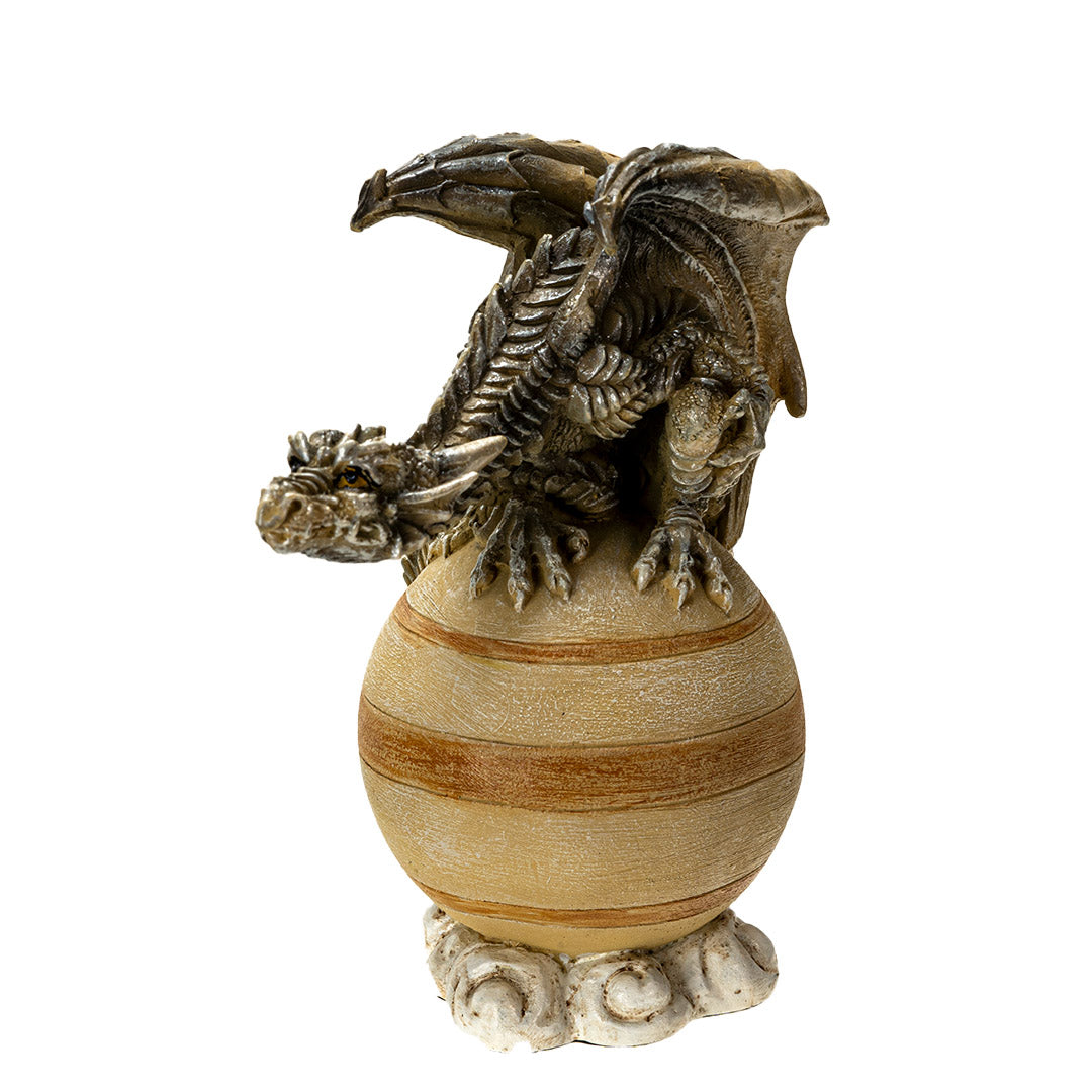 Figurine of a brown dragon perched upon the tan planet Saturn on a cloud base