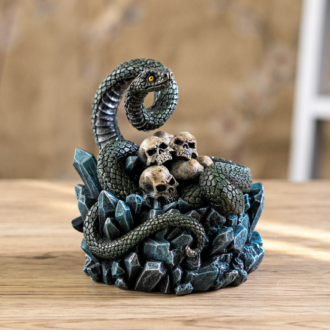 Trinket box, blue crystals on base with yellow-eyed green snake twining through human skull pile