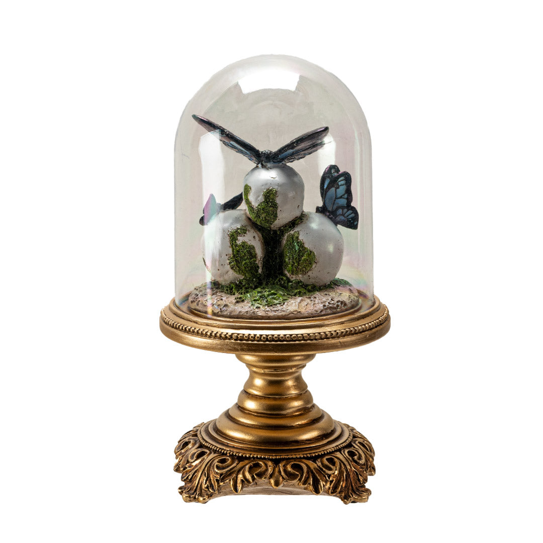 Figurine with three skulls and blue-black butterflies perched on them, moss accents, under a glass cloche dome on an ornate gold base