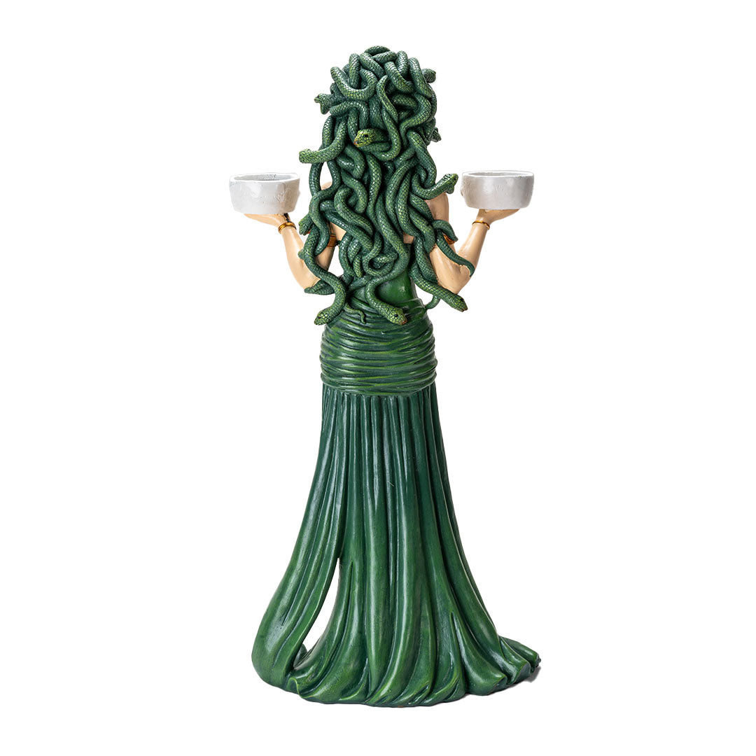 Figurine of Medusa with green snakes for hair, green and gold dress, holding two skull bowls that can hold candles, shown from the back