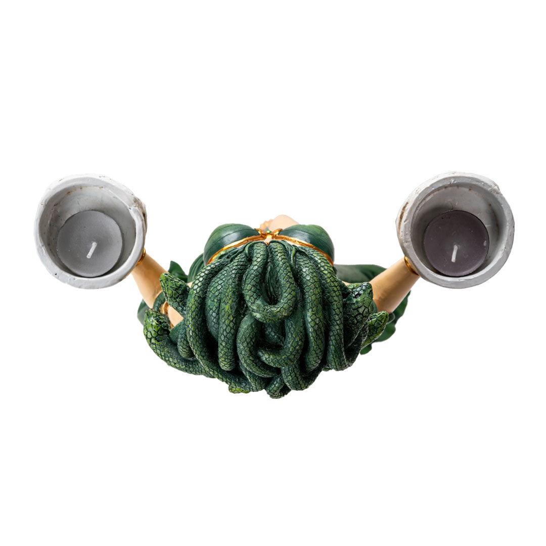 Figurine of Medusa with green snakes for hair, green and gold dress, holding two skull bowls that can hold candles, shown top down