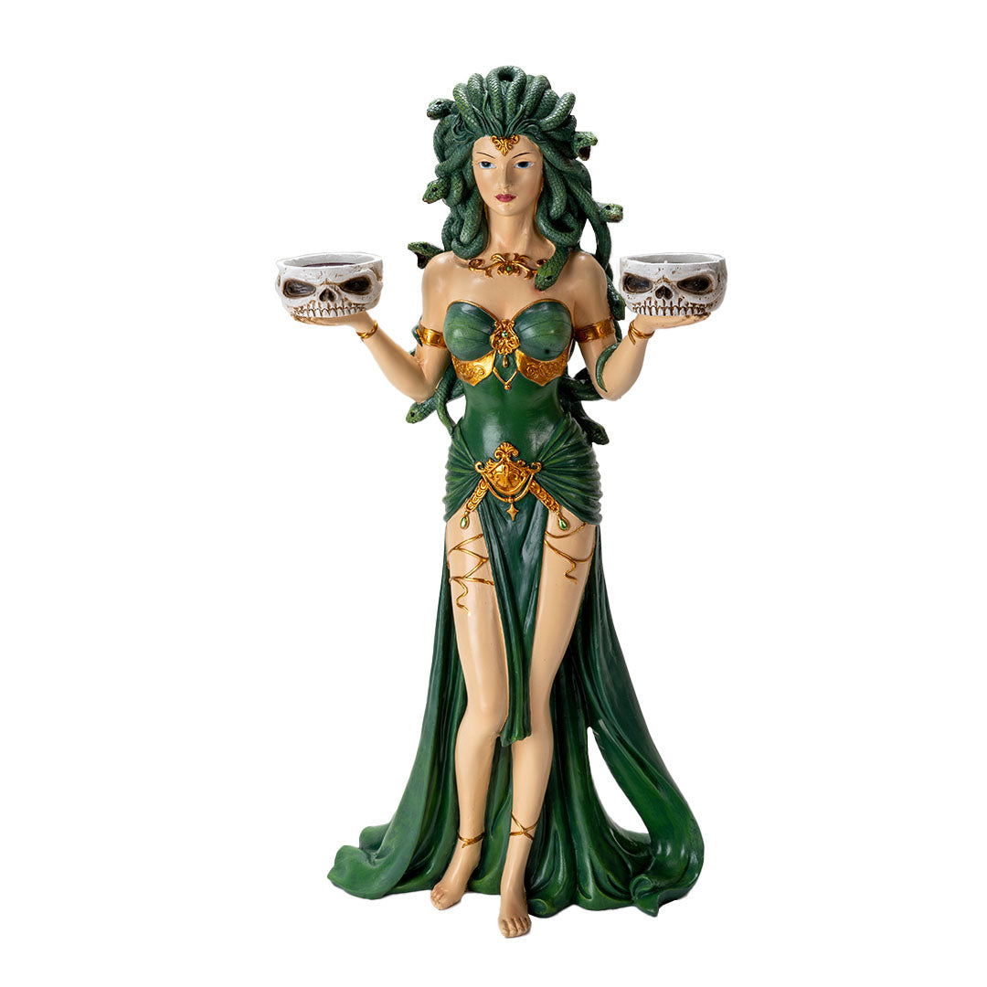 Figurine of Medusa with green snakes for hair, green and gold dress, holding two skull bowls that can hold candles
