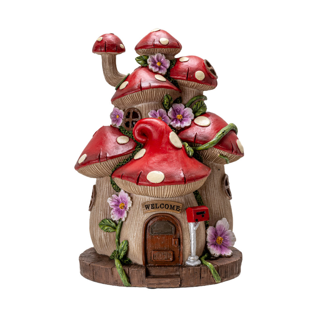 Figurine of a house made of mushrooms (red with white spotted caps) and pink flowers, door and welcome sign with mailbox