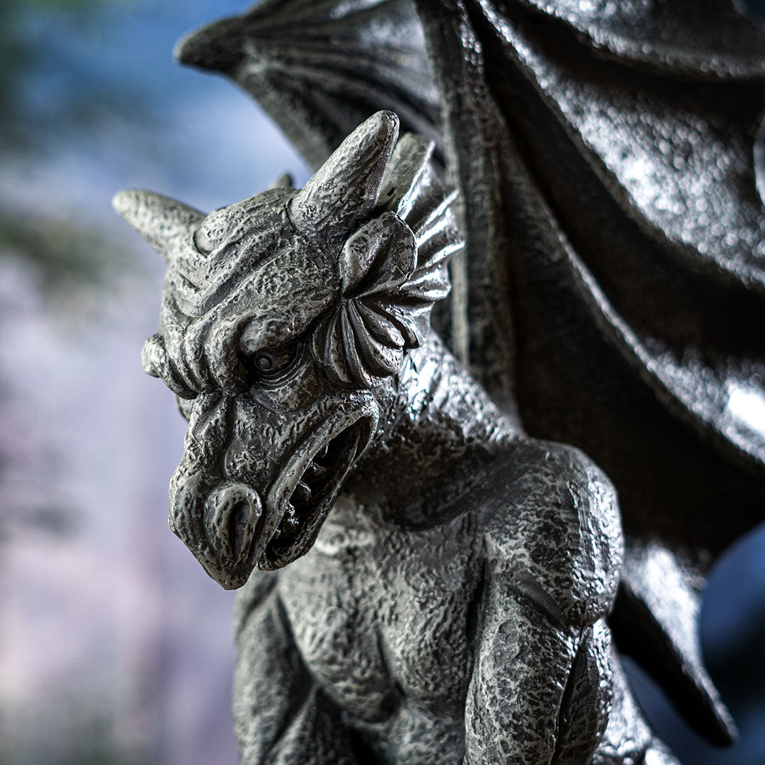 Figurine of a gray faux-stone gargoyle with dragon wings, closeup of face
