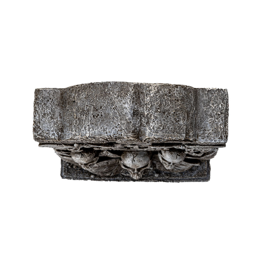 Figurine of gray faux-stone tombstone with butterflies, RIP, skulls and leaves, top down view