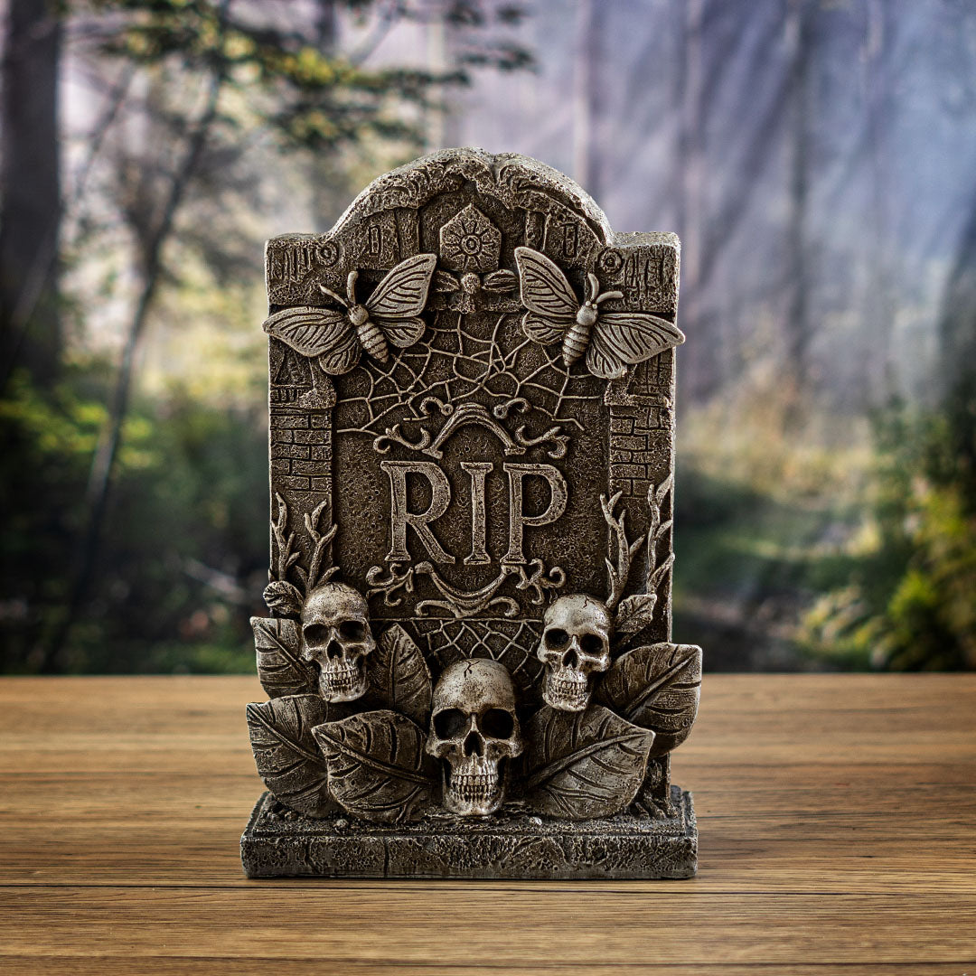 Figurine of gray faux-stone tombstone with butterflies, RIP, skulls and leaves