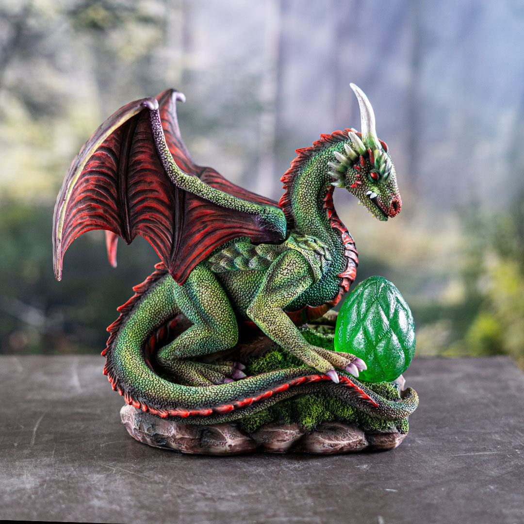 Figurine of green dragon with red wings, spines, eyes and belly, with an egg in front that can glow with LED lighting