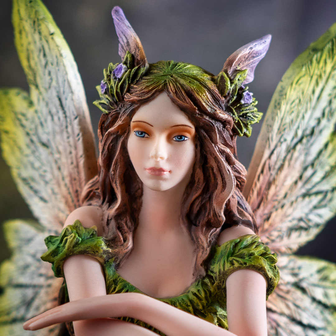 Closeup of fairy figurine, brown hair with flowers in it, blue eyes