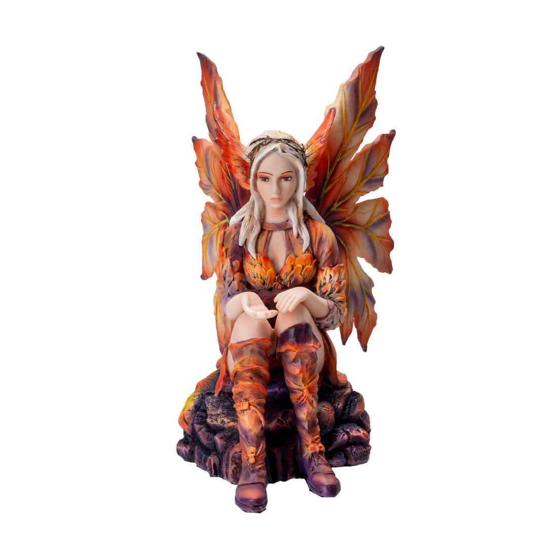 Figurine of blond fairy with orang wings and outfit sitting on a rock with her hand out, palm up