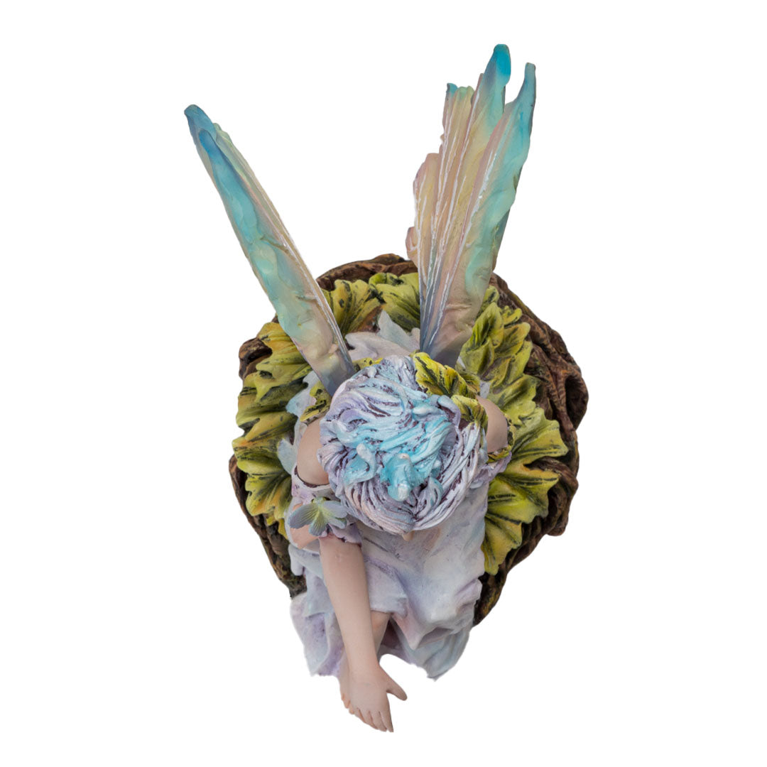 Figurine of pale fairy with pastel wings and hair seated on leafy roots, shown top down