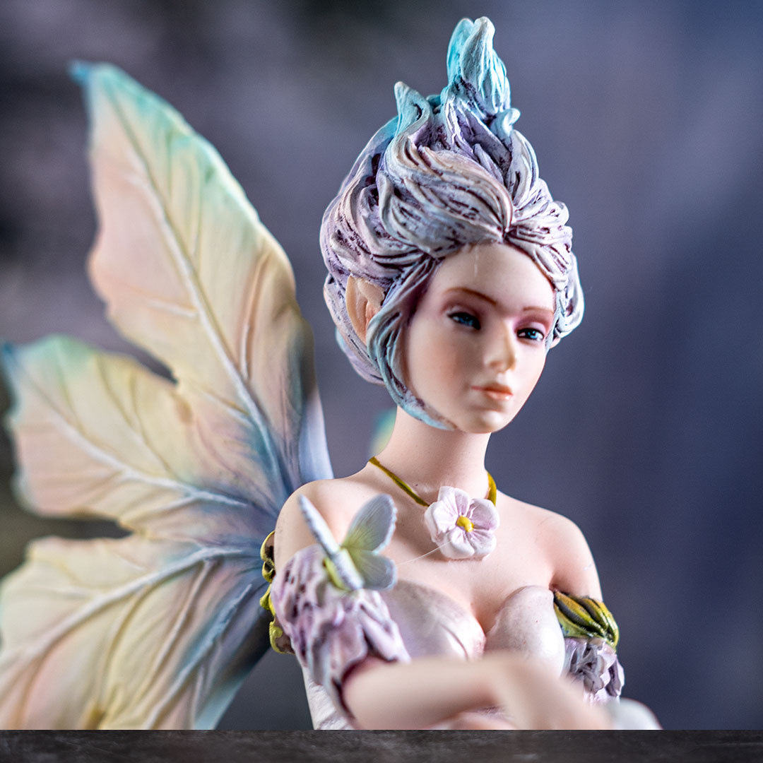 Figurine of pale fairy with pastel wings and hair with a butterfly and flower necklace, close up of face